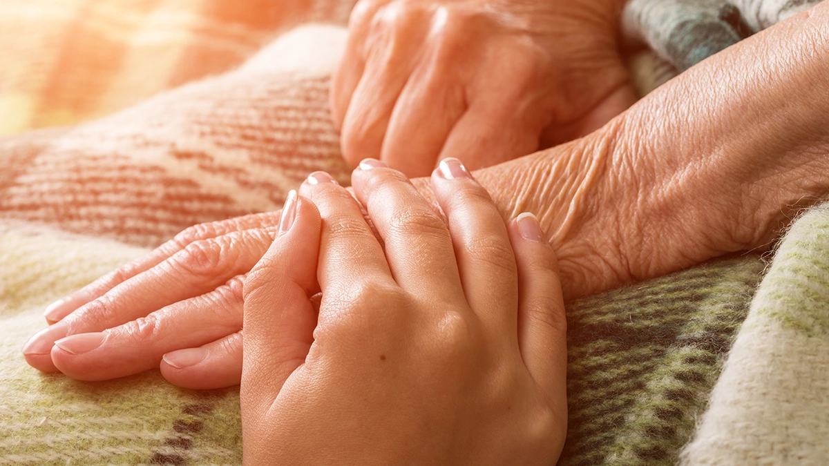 2024 03 13 Daughter grasping her elderly parents hand who is in hospice care.